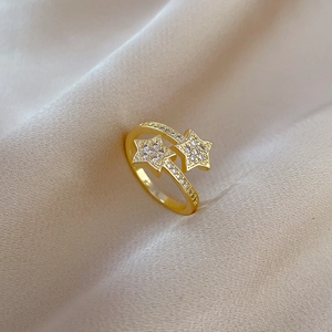 Detailed close-up of gold-plated star ring with white zircon on beige silk fabric