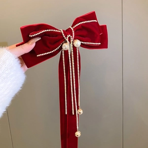 Detail of red velvet bow hair clip with white pearls and sparkling rhinestone tassels
