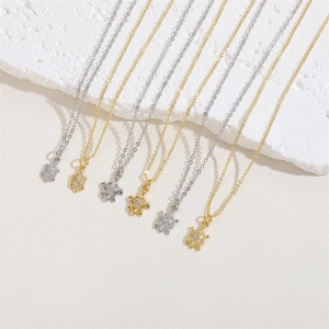 Detailed view of turtle pendants with clear zircon stones on a white textured stone