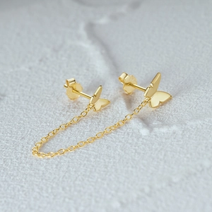 Macro shot of 925 silver gold-plated butterfly chain earrings with polished finish