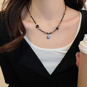 Detailed view of beaded necklace featuring black beads and round silver butterfly pendant