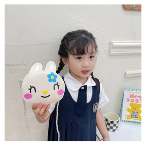 Detail of cute cream cartoon rabbit shoulder bag worn by a child with floral accents
