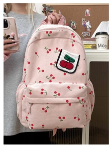 Zaino in velluto a coste rosa con ricamo a ciliegia tenuto in uno studio