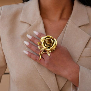 Close-up of a large gold rose flower ring with detailed layered petals on a hand