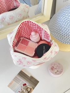 Quilted cotton makeup bag with pink bow pattern and checkered lining on vanity