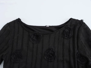 Détail d'un haut élégant en dentelle noire avec fleurs roses 3D et texture rayée