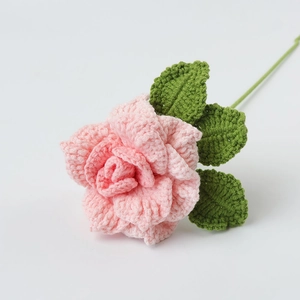 Detailansicht handgehäkelter rosa Rosenblüten und grüner Blätter aus hochwertigem Baumwollgarn