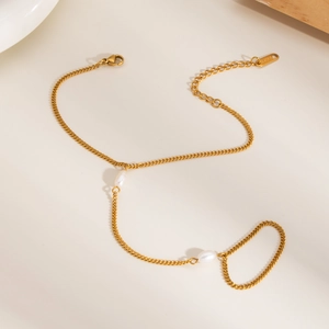 Détail d'un bracelet bague en acier inoxydable doré avec perles sur fond minimaliste