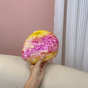 Detail of pink and yellow marble pattern clutch bag with glossy oval pebble shape