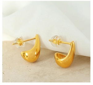 Macro shot of polished gold water drop earrings with a reflective metallic finish