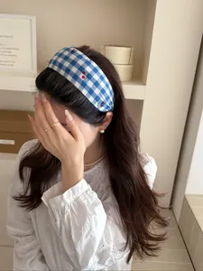 Close-up of blue and white plaid headband with cherry print worn by a model