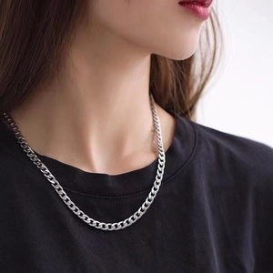 Close-up of a silver cuban link chain worn by a male model over a black t-shirt