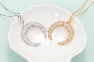 Crescent moon pendant necklace with micro-paved zircons in gold and silver finishes