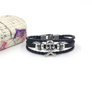 Macro detail of multi-layer leather bracelet with silver skull charm and metal beads