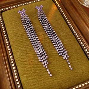 Vue détaillée des longues boucles d'oreilles à pompons violets avec strass sur velours