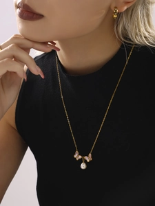 Gros plan du collier papillon doré avec coquillages roses et perles sur un mannequin