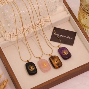 Natural stone tree of life necklaces in amethyst, rose quartz, and tiger eye on gold tray