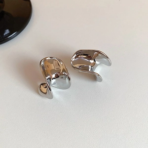 Close-up of silver C-shaped metal earrings with irregular liquid streamlined design