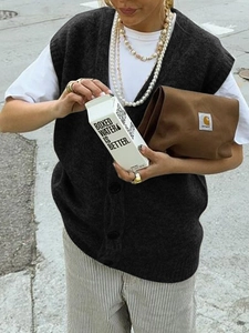 Foto lifestyle di una donna con gilet nero in maglia bottoni e accessori alla moda