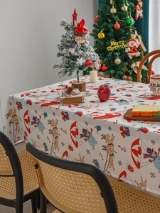 Detailed close-up of Nordic Christmas tablecloth with Santa and reindeer prints on beige fabric