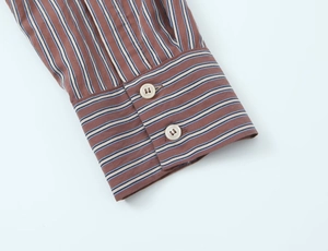 Detailed close-up of striped poplin shirt cuffs with two white resin buttons