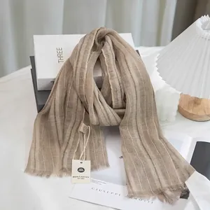 Close-up of light brown linen cotton scarf featuring vertical stripes and fringe tassels
