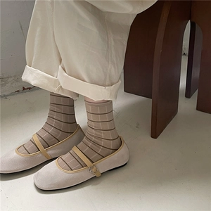 Close-up of brown striped crew socks paired with beige Mary Jane flats and rolled pants