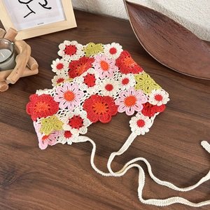 Handmade crochet floral bandana with colorful knit daisies on a rustic wood background