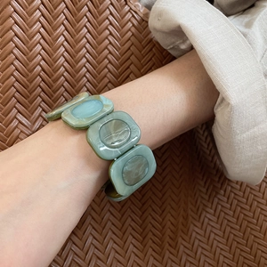 Detailed view of teal marble resin square links on a wide stretch bracelet for women
