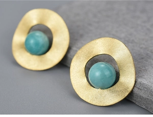 Macro shot of minimalist gold irregular earrings featuring round blue natural stone beads