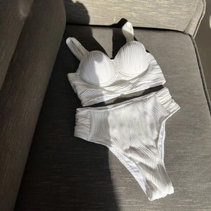 Close-up of white high-waisted bikini set with textured ribbed fabric and pleated details