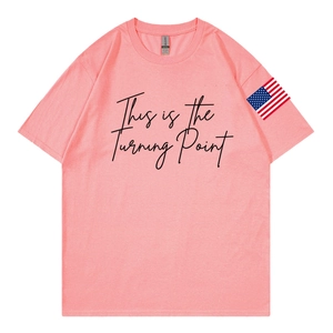 Dettaglio della t-shirt rosa corallo con scritta nera e patch della bandiera USA sulla manica