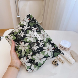 Detail of floral zipper pouch showing black jacquard fabric and simple wish label