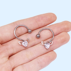 Macro shot of silver horseshoe rings with winged heart zircons held in hand