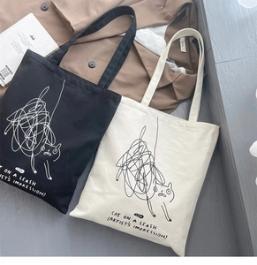 Detail of canvas tote bags in black and cream featuring artistic cat doodle line art