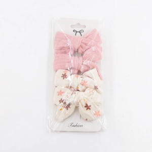 Detail view of four pieces floral and pink fabric bow hair clips set in packaging