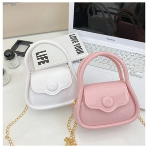Mini macaron jelly bags in white and pink with elegant gold chain straps on a modern desk