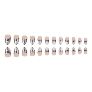 Almond shaped press-on nails with nude base, black polka dots and bow tie designs