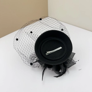 Detail of vintage black fascinator hat with polka dot mesh veil and feather trim