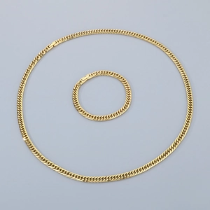 Close-up of golden dual-weave cuban link chain necklace and bracelet set in polished steel