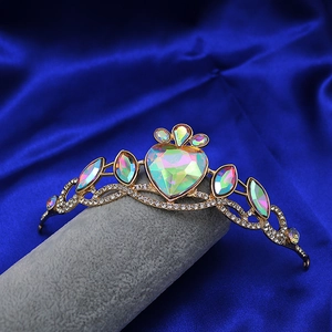 Detailed close-up of golden heart crown headband with AB crystals on blue silk background
