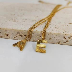 Close-up of golden stainless steel pendants with letter A and E textured engraving