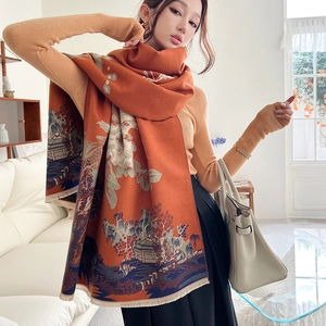 Detailed close-up of thick orange cashmere scarf with intricate floral patterns