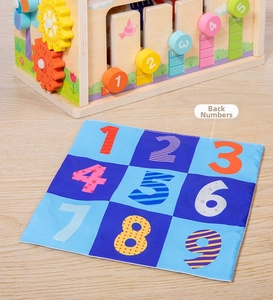 Detail of wooden activity cube with sliding numbers and a colorful 1-9 numbered play mat