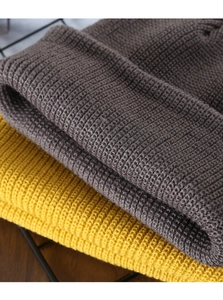 Detailed close-up showing the knit texture and stitching of grey and yellow beanie hats