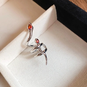 Macro shot of silver snake ring with red zircon stone eyes in a textured jewelry box