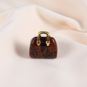 Macro detail of a mini handbag-shaped red natural stone pendant with a gold handle