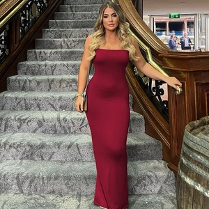 Detail of burgundy backless slim fit maxi dress featuring a sexy cutout on a luxury staircase