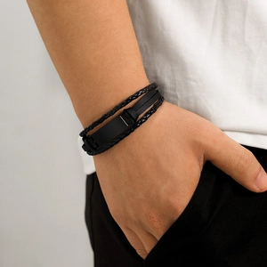 Close-up of men's multi-layer black braided leather bracelet with metal clasp on wrist