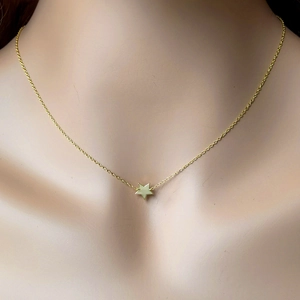 Close-up of minimalist gold star pendant necklace worn by a model for elegant styling